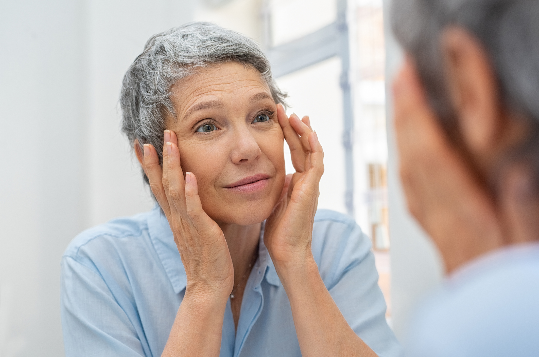 Mature woman examining her face in the mirror